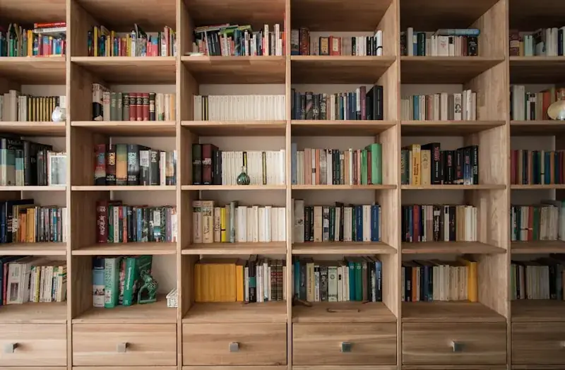 Wall-to-wall oak built-in bookshelves filled with books, with a row of drawers across the bottom