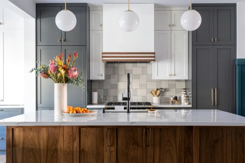Two-tone kitchen with charcoal floor-to-ceiling cabinets, white uppers, a patterned tile backsplash, and a walnut island